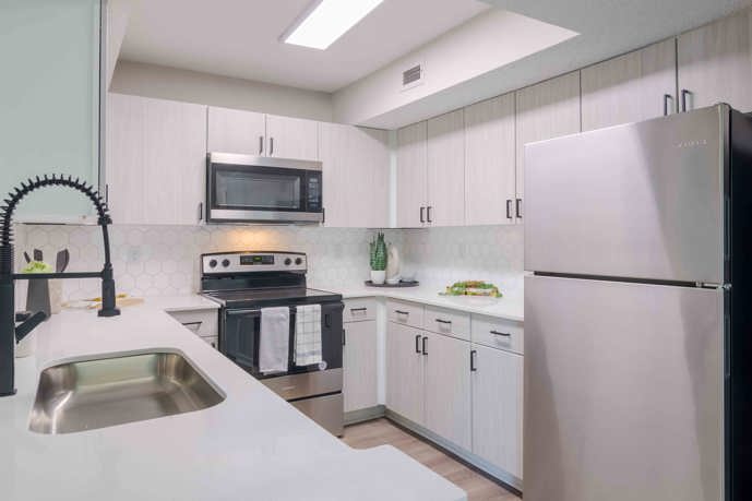 Brightly lit white apartment kitchen with stainless steel appliances